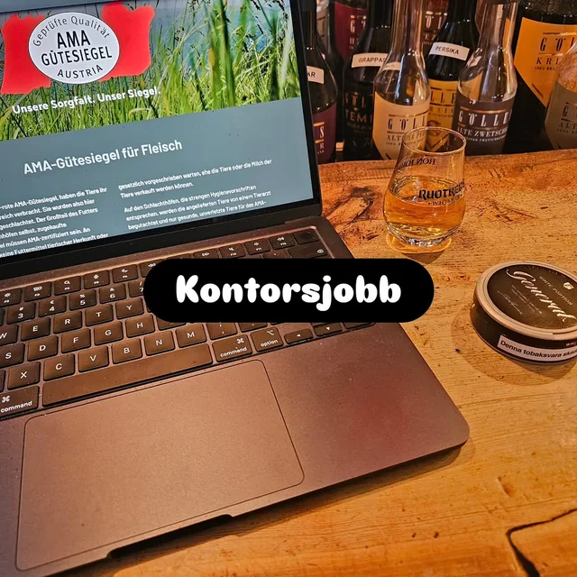 En laptop på ett furubord med texten Kontorsjobb, bredvid ett glas och en liten burk