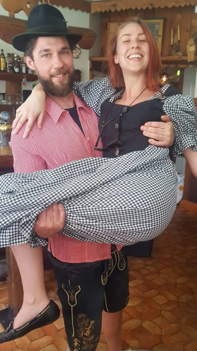 Man i lederhosen som bär en skrattande kvinna i famnen
